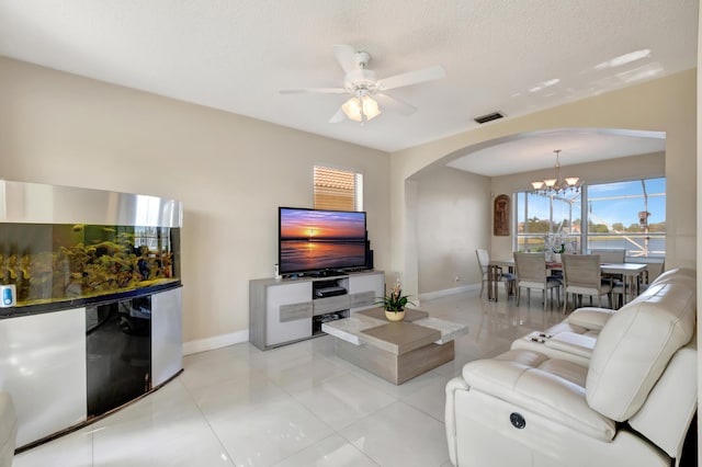 living room featuring light tile patterned floors, ceiling fan with notable chandelier, and a textured ceiling