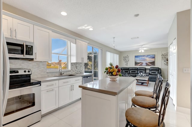 kitchen with stainless steel appliances, white cabinetry, a center island, and sink