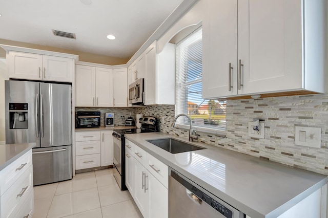 kitchen featuring tasteful backsplash, appliances with stainless steel finishes, sink, and white cabinets