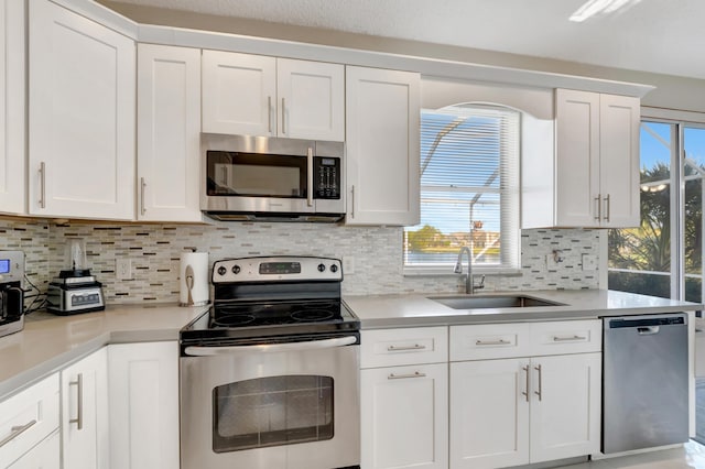 kitchen featuring appliances with stainless steel finishes, sink, white cabinets, and decorative backsplash