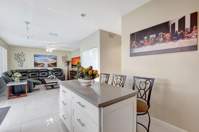 kitchen featuring white cabinetry, a kitchen island, a breakfast bar, and light tile patterned floors