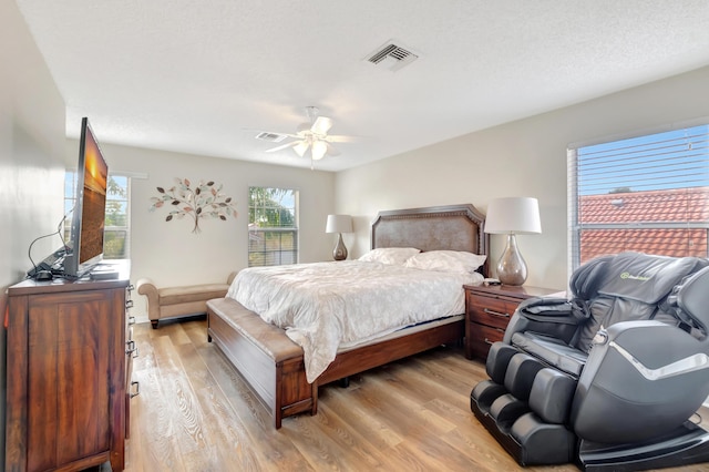 bedroom featuring ceiling fan, a textured ceiling, and light hardwood / wood-style floors