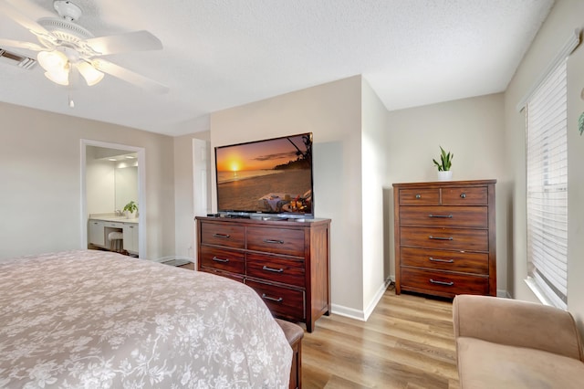 bedroom with multiple windows, ensuite bathroom, a textured ceiling, and light hardwood / wood-style floors