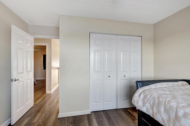 bedroom with dark hardwood / wood-style flooring, a closet, and a textured ceiling