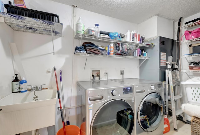 clothes washing area featuring sink, washer and dryer, and a textured ceiling