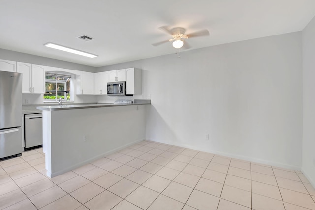 kitchen featuring kitchen peninsula, light tile patterned flooring, white cabinets, and stainless steel appliances