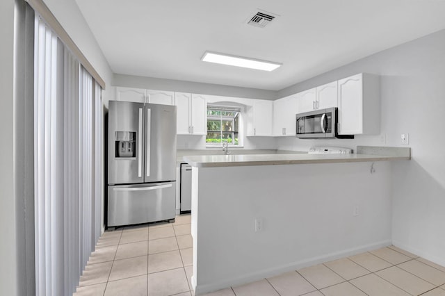 kitchen featuring white cabinets, light tile patterned flooring, kitchen peninsula, and appliances with stainless steel finishes