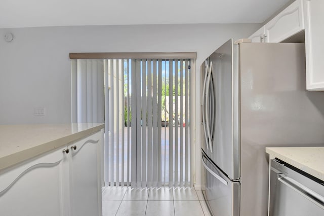 kitchen with white cabinets, light tile patterned flooring, light stone countertops, and stainless steel appliances