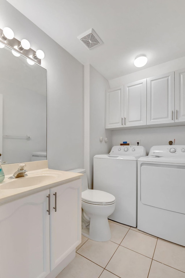 bathroom featuring washing machine and clothes dryer, tile patterned floors, vanity, and toilet