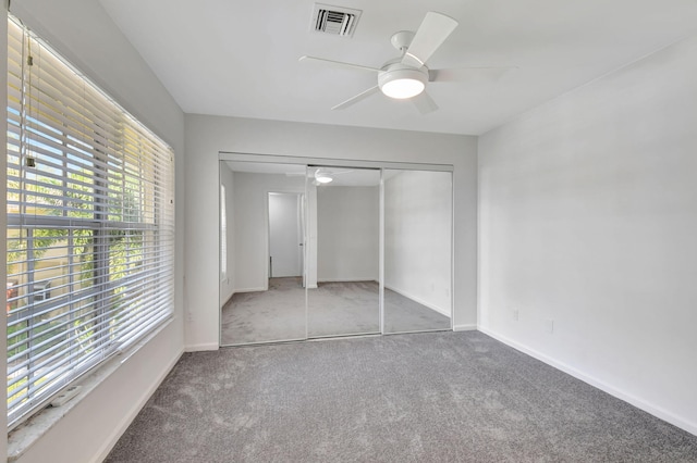 unfurnished bedroom with multiple windows, ceiling fan, a closet, and light carpet