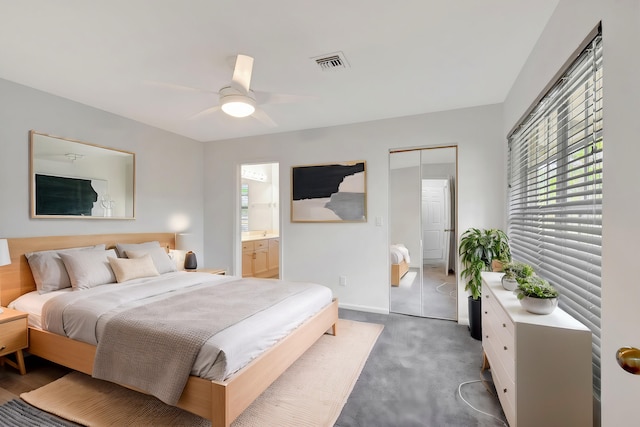 carpeted bedroom featuring a closet, ensuite bath, and ceiling fan