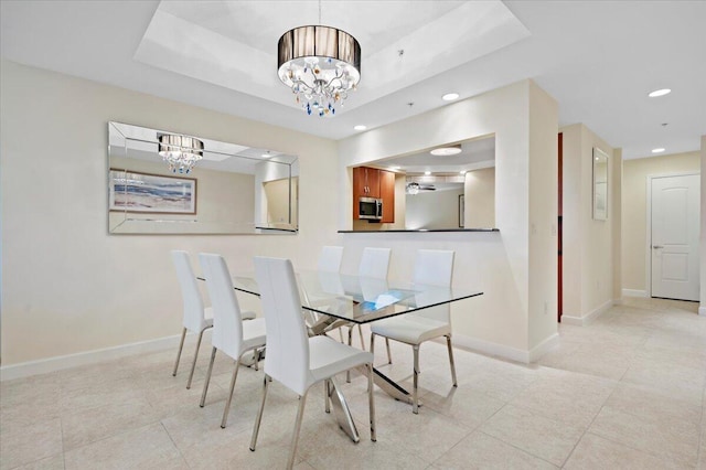 tiled dining room with a tray ceiling and an inviting chandelier