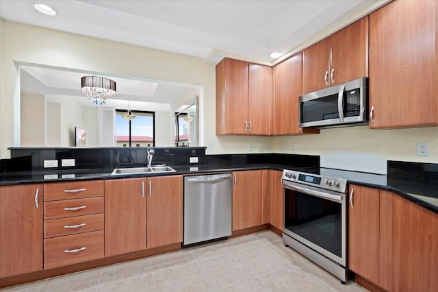 kitchen with sink, an inviting chandelier, dark stone countertops, pendant lighting, and appliances with stainless steel finishes