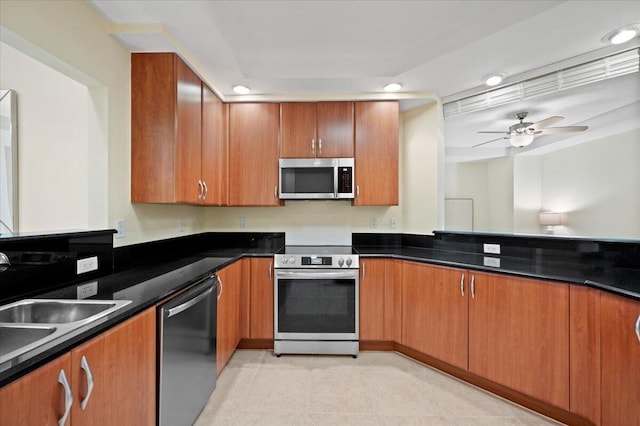 kitchen with dark stone counters, ceiling fan, sink, and stainless steel appliances