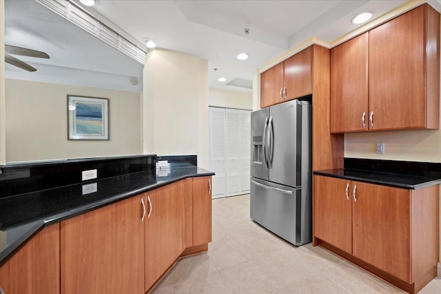 kitchen with stainless steel fridge, ceiling fan, and dark stone countertops