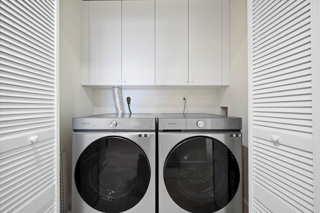 laundry area with separate washer and dryer and cabinets