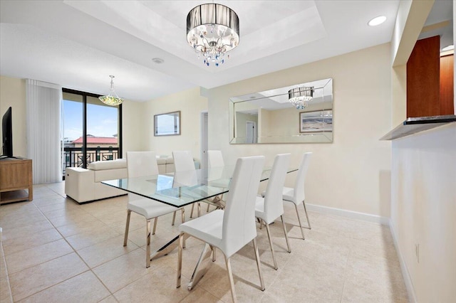 tiled dining space featuring a chandelier and a tray ceiling