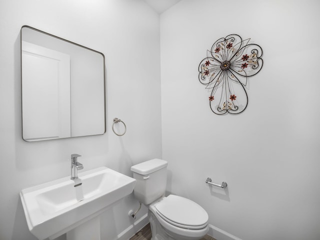 bathroom with a sink, toilet, and baseboards