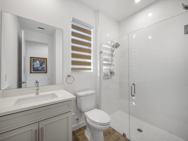 bathroom featuring vanity, hardwood / wood-style flooring, toilet, and a shower with shower door