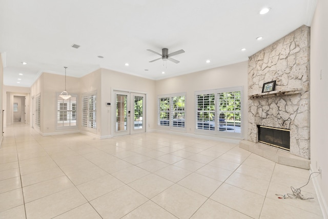 unfurnished living room featuring ceiling fan, a fireplace, ornamental molding, light tile patterned floors, and french doors