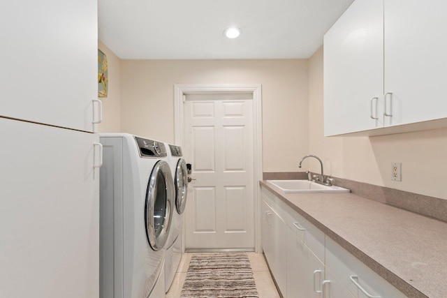 laundry room with light tile patterned floors, sink, washing machine and clothes dryer, and cabinets