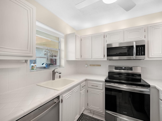 kitchen featuring decorative backsplash, appliances with stainless steel finishes, sink, tile countertops, and white cabinets