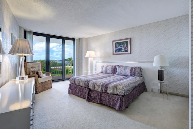 carpeted bedroom with access to exterior, a textured ceiling, and a wall of windows