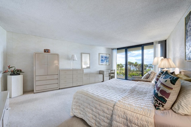 bedroom featuring light colored carpet, a wall of windows, a textured ceiling, and access to outside