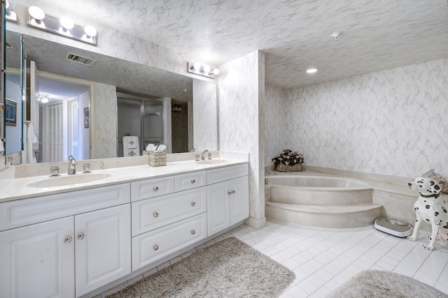 bathroom with a textured ceiling, vanity, tile patterned floors, and separate shower and tub