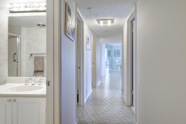 corridor featuring sink and a textured ceiling