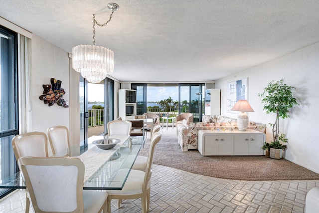 dining area with floor to ceiling windows, a textured ceiling, and a chandelier