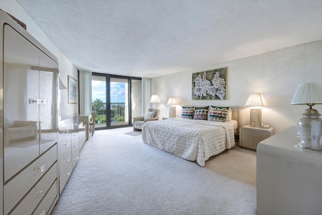 bedroom featuring a textured ceiling, floor to ceiling windows, and light carpet