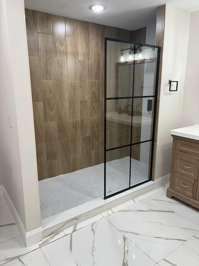 bathroom with vanity, a textured ceiling, and a tile shower