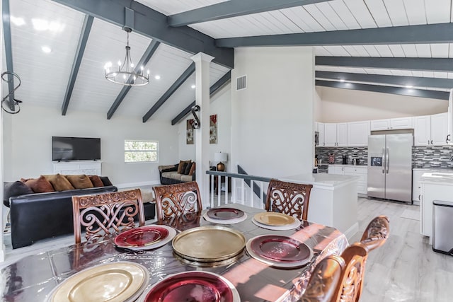 dining space with a chandelier, lofted ceiling with beams, and light hardwood / wood-style floors