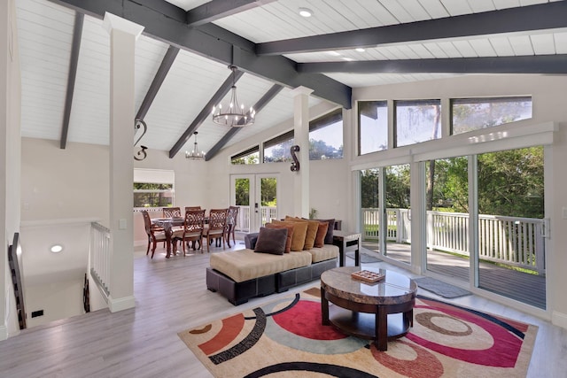 living room with a chandelier, light wood-type flooring, high vaulted ceiling, and french doors