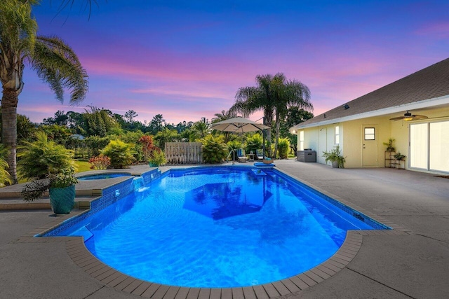 pool at dusk with a patio area and an in ground hot tub