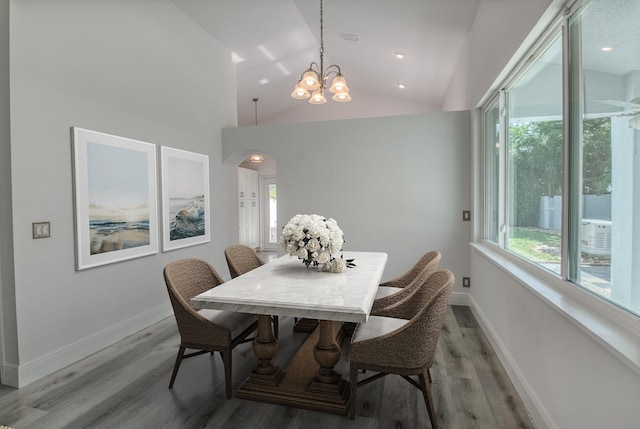 dining room featuring hardwood / wood-style flooring, a chandelier, high vaulted ceiling, and a wealth of natural light