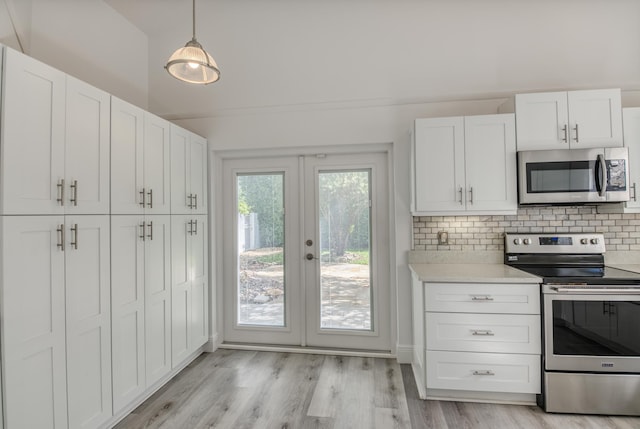 kitchen with light hardwood / wood-style floors, white cabinetry, hanging light fixtures, decorative backsplash, and stainless steel appliances