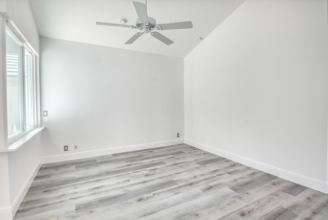 empty room featuring light hardwood / wood-style flooring, vaulted ceiling, and ceiling fan