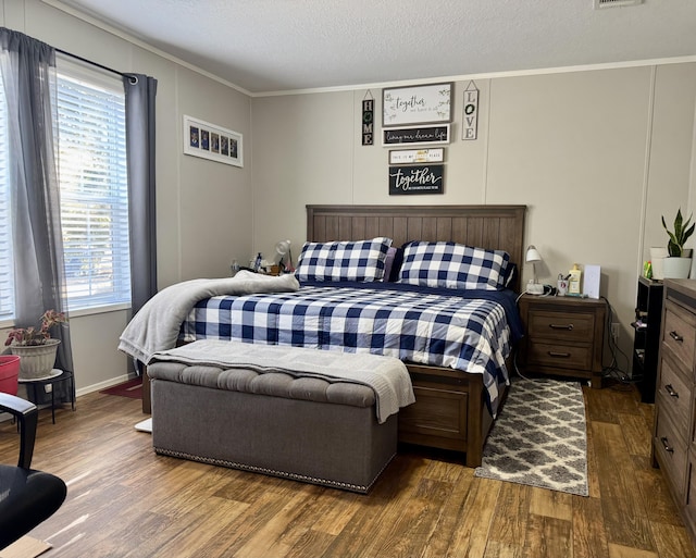 bedroom featuring a textured ceiling, hardwood / wood-style flooring, multiple windows, and ornamental molding