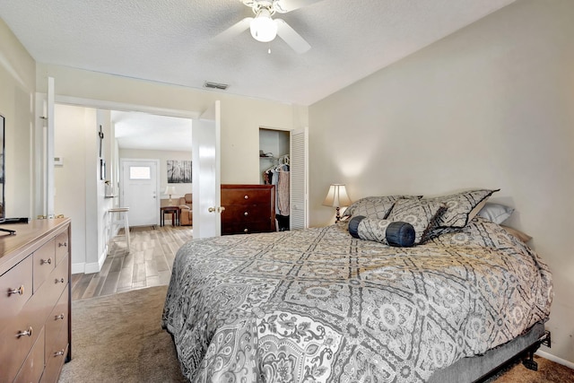 bedroom with a textured ceiling, carpet floors, a closet, and ceiling fan