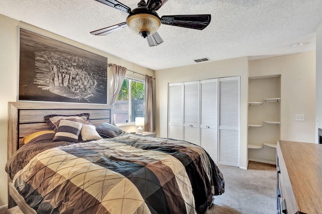 carpeted bedroom featuring ceiling fan and a textured ceiling