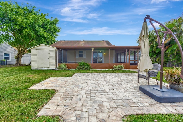 rear view of property featuring a sunroom, a storage shed, a yard, and a patio