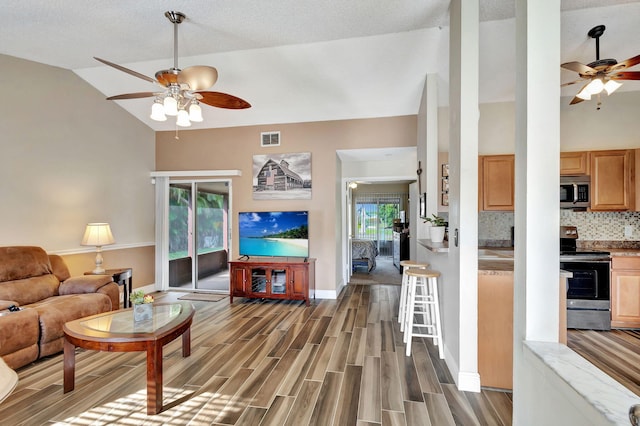 living room featuring a wealth of natural light, dark wood-type flooring, and ceiling fan