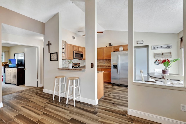 kitchen featuring a textured ceiling, decorative backsplash, dark hardwood / wood-style floors, and appliances with stainless steel finishes