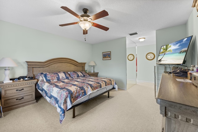 bedroom featuring a textured ceiling, ceiling fan, and light colored carpet