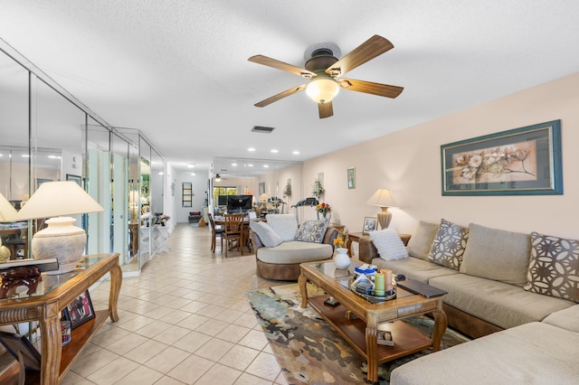 living room featuring a textured ceiling, ceiling fan, and light tile patterned flooring