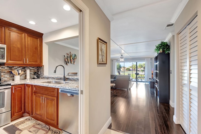 kitchen with sink, ornamental molding, appliances with stainless steel finishes, tasteful backsplash, and wood-type flooring