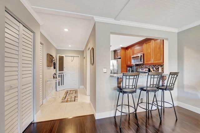 kitchen featuring kitchen peninsula, a breakfast bar, stainless steel appliances, and crown molding