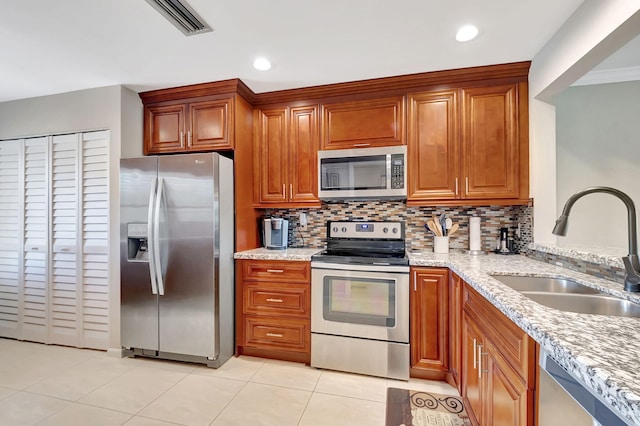 kitchen featuring appliances with stainless steel finishes, tasteful backsplash, light stone counters, and sink